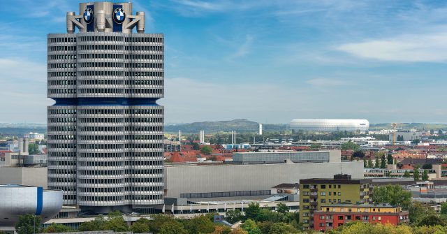 Der BMW-Turm (BMW-Vierzylinder oder BMW-Turm), im Hintergrund die Allianz Arena, Fußballstadion (Fußball Arena München, Schlauchboot) in München, Deutschland