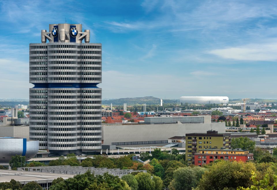 Der BMW-Turm (BMW-Vierzylinder oder BMW-Turm), im Hintergrund die Allianz Arena, Fußballstadion (Fußball Arena München, Schlauchboot) in München, Deutschland