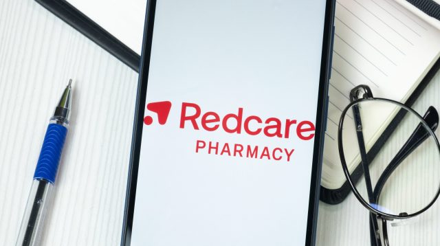 Redcare Pharmacy Logo auf dem Handy am Schreibtisch