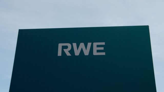 Ein blaues RWE-Schild mit blauem Himmel vor dem Wasserkraftwerk in Heimbach, Deutschland