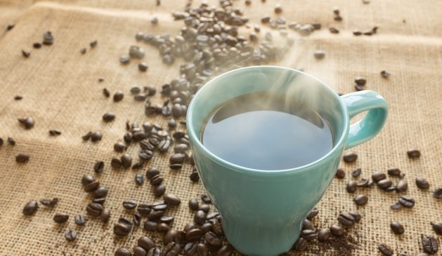 Kaffetasse welche auf einem Tisch mit Kaffebohnen steht