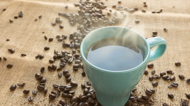 Kaffetasse welche auf einem Tisch mit Kaffebohnen steht