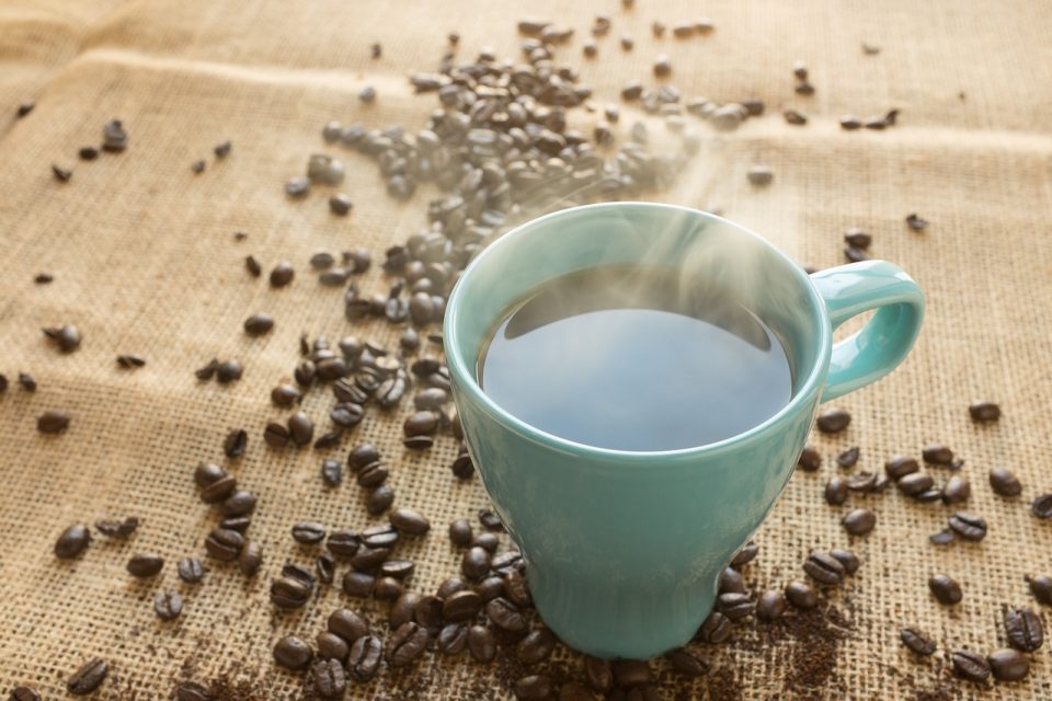 Kaffetasse welche auf einem Tisch mit Kaffebohnen steht