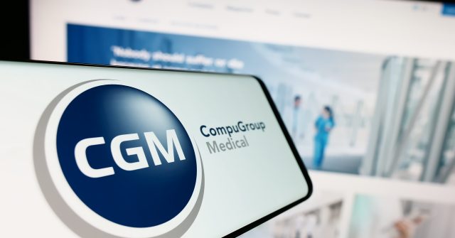 Ein Mobiltelefon mit Logo der Firma CompuGroup Medical SE Co. KGaA (CGM) auf dem Bildschirm vor einer Website mit Fokus auf die Mitte links des Telefondisplays