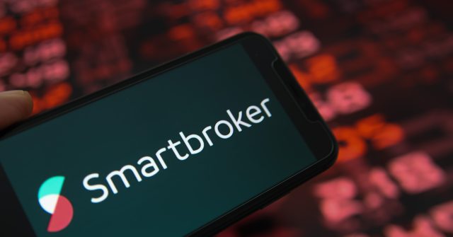 Nahaufnahme des Handy-Displays mit Logo-Schriftzug von Smartbroker, Börsenchart im Hintergrund