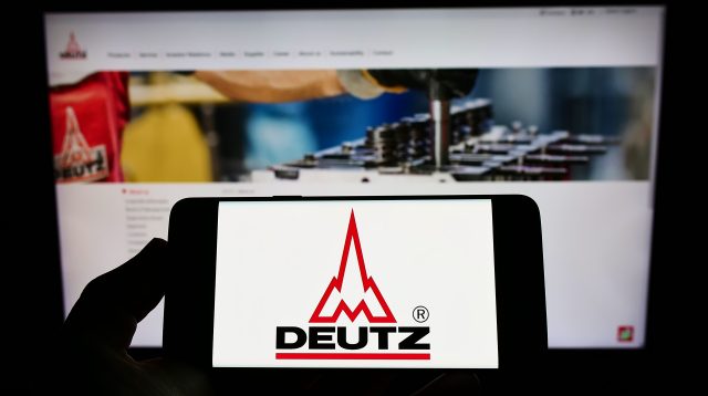 Person hält Smartphone mit Logo des deutschen Motorenherstellers Deutz AG auf dem Bildschirm vor einer Website mit Fokus auf das Telefondisplay