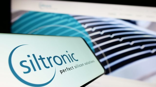 Mobiltelefon mit dem Logo des deutschen Elektronikunternehmens Siltronic AG auf dem Bildschirm vor einer Unternehmenswebsite mit Fokus auf die Mitte links des Telefondisplays