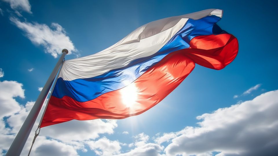 Russische Flagge weht im Wind auf blauem Himmel mit der Sonne im Hintergrund