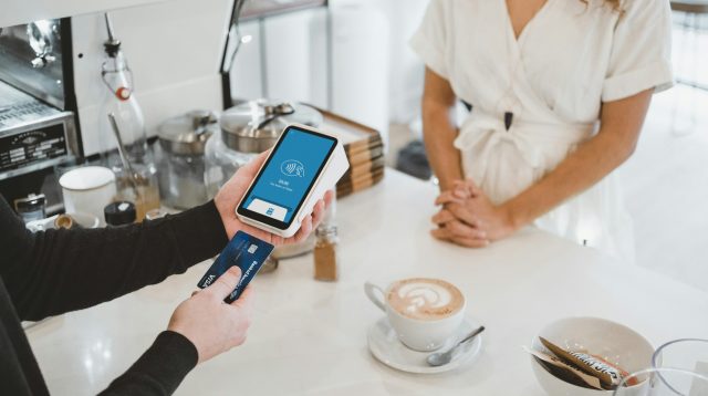 Ein Mann zahlt in einem Café mit seiner Karte