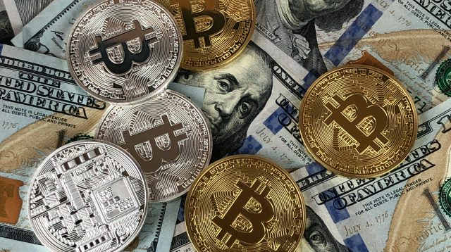 Bitcoin als Gold- und Silbermünze auf 100-Dollar-Noten